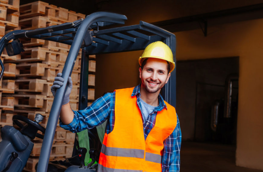 Construction worker posing near forklift