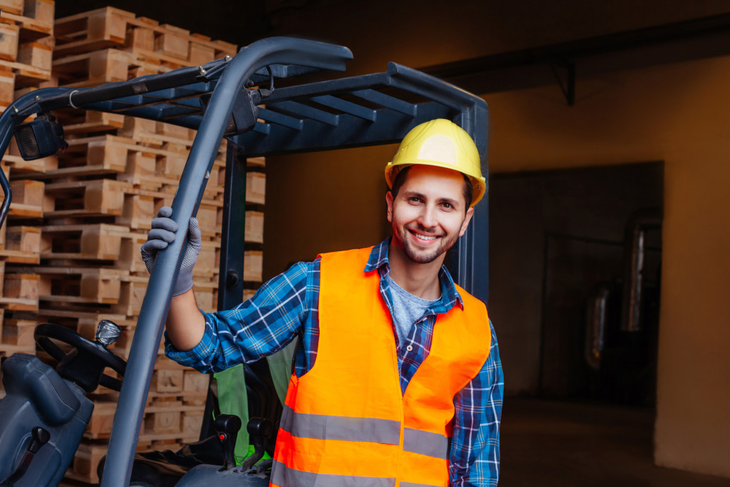 Construction worker posing near forklift