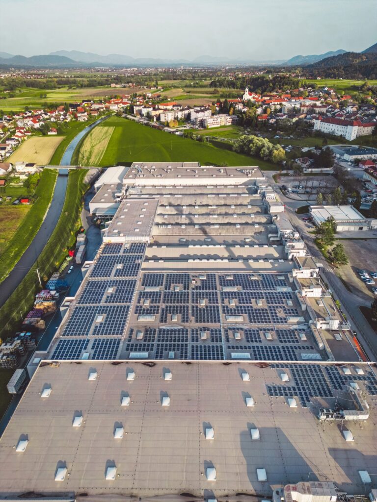 Vertical photo of large industrial area with multiple factories, roof tops covered with solar panels